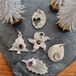 Four Silver Pendants lined up on a wooden background