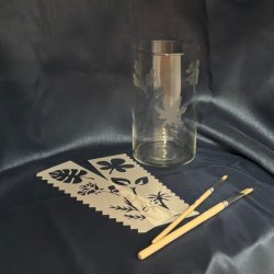 Glass vase with 3 etchings, 2 stencils and 2 brushes displayed on dark blue fabric
