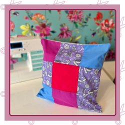 A patchwork cushion with a sewing machine in the background