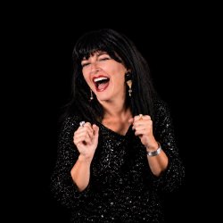 promotional square for “Roxy Bellows Live!” featuring Roxy smiling in a black sequined outfit, surrounded by bright gold marquee-style lettering and sparkling gold accents on a theatrical background