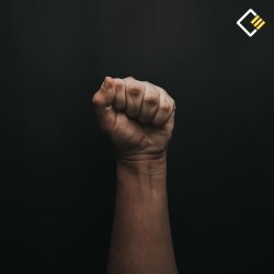 A clenched fist is raised against a dark background, symbolising strength or protest. The lighting highlights the hand's texture, conveying determination. The Cooper Education logo appears.
