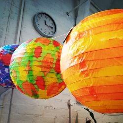 3 painted, colourful lanterns are strung up in a room in a room