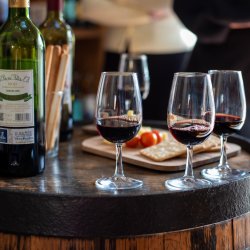 3 glasses of red wine on a barrel with a cheese board