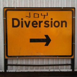A diversion sign that has Joy graffitied at the top