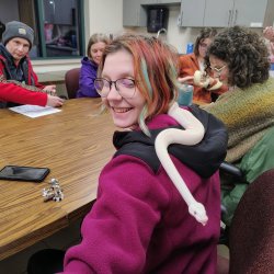 Adult Camp participant smiling as a snake moves across her back
