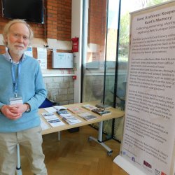 Middle age man in blue jumper standing by an information board