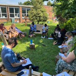 A group of people sitting in the garden at Hodge Hill Church working on poems during a recent workshop
