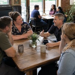 Men and women sat talking and listening in casual environment