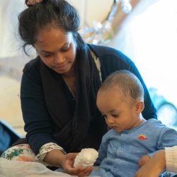 A young baby and their carer playing with a musical instrument
