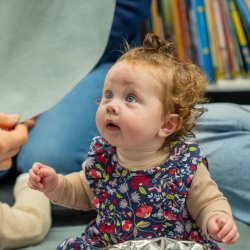 A young baby looking up amazed at their own reflection.
