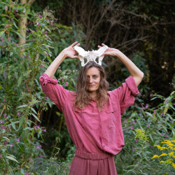 A woman holding pelvic bones like a crown, looking into the camera.