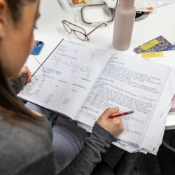Student studying making notes in notebook