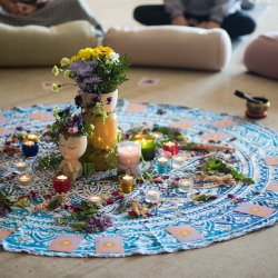 Mandala mat with flowers, candles and oracle cards on