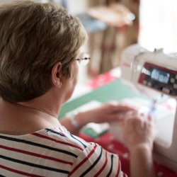 Looking over the shoulder of a woman using a sewing machine