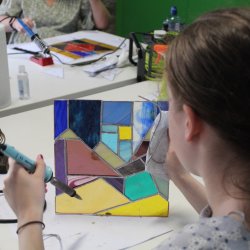 Woman holding her stained glass panel upto the light