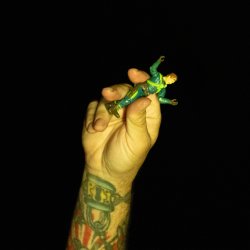 a tattooed hand holding a figurine
