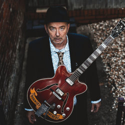 Francis Dunnery dressed smartly with a Hofner Guitar
