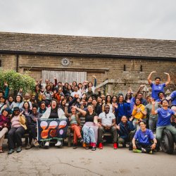 Image of a crowd of people of colour in front of a barn
