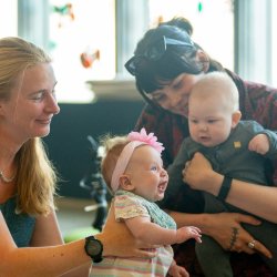 Two young babies attend a Baby Playground session with their carers, sharing a calm, playful moment together.