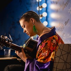 A picture of a emma langford  playing guitar