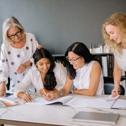 Four women in an office looking over papers together.