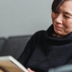 A woman in her 50's smiles as she writes in her journal