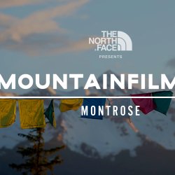 The North Face presents Mountainfilm on Tour Montrose, with colorful prayer flags in front of snow-covered mountain peaks.
