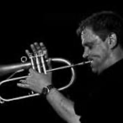 Jazz trumpeter playing trumpet in black and white with dramatic side lighting against a dark background
