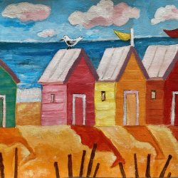 Four different coloured beach huts on a sandy beach with flags and a seagul.
