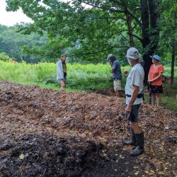 Tom Vigue leads a group of people on a tour of his leaf compost piles