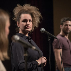 Drei Personen stehen an einem Mikrofon