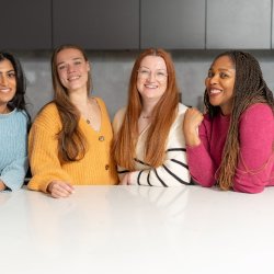an image of the four female dietitians at Mental Health Dietitians, wearing bright colours, stood in a kitchen, similing at the camera.