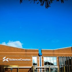 Exterior of the Science Creates building, Bristol, beneath a blue sky.