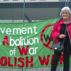 A supporter standing in front of the MAW banner outside an arms fair