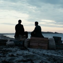 Paul Cuffe and Michael Wainer sitting on the beach watching the sun come up