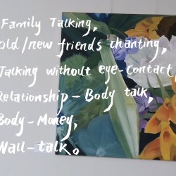 A film still image of a white wall with flower paintings hung on it. White, poetic text is overlaid on the image.