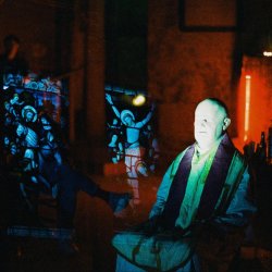 A double exposed photograph, depicting the artist dressed as a priest, overlaid with stained glass windows.