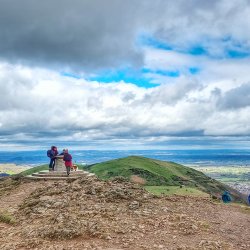 People stand at Worcestershire Beacon, with epic views of several counties beyond