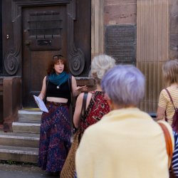 A photograph showing a tour guide talking to a group of people