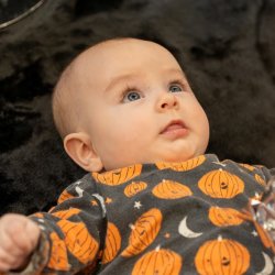 A young baby lying on their back on a textured black rug looking up.
