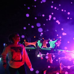 Woman looks at fog bubbles under black lights.