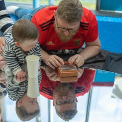 A young baby and their carer playing with a musical instrument
