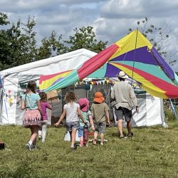 A picture of Friends outdoors socializing, near a colourful open-sided tent.