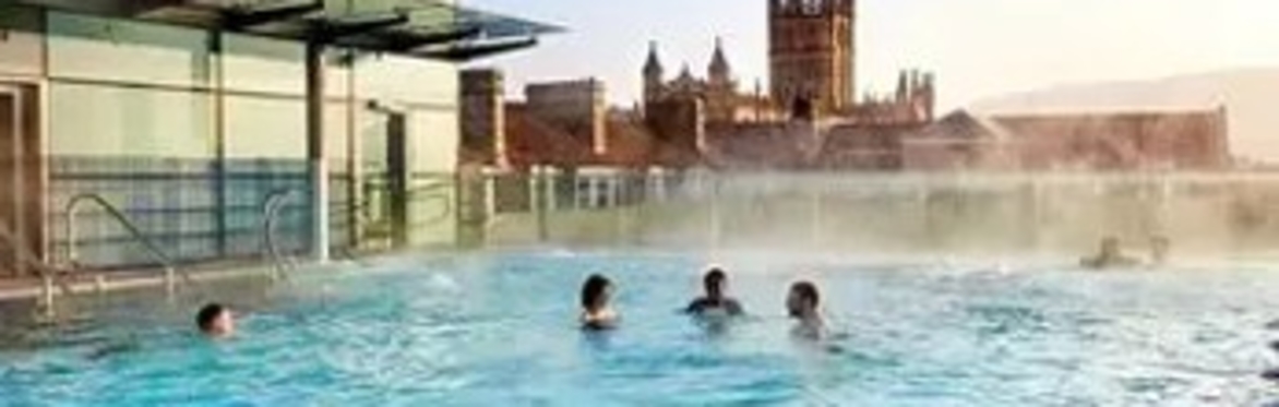 swimmers in the rooftop pool at Bath's Thermae spa with a view of the Abbey beyond