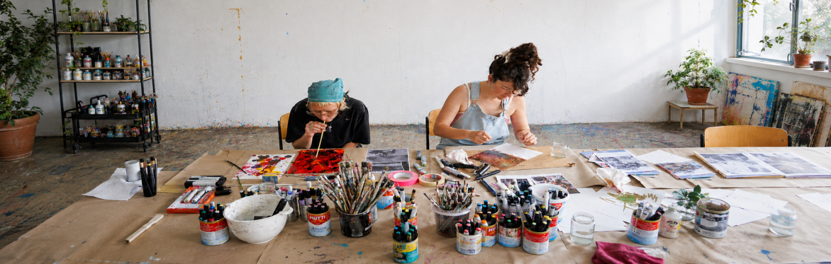 Two participants creating colorful alcohol ink artworks in a bright artist studio.