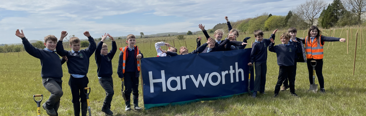 A picture of children cheering in front of a Harworth sign