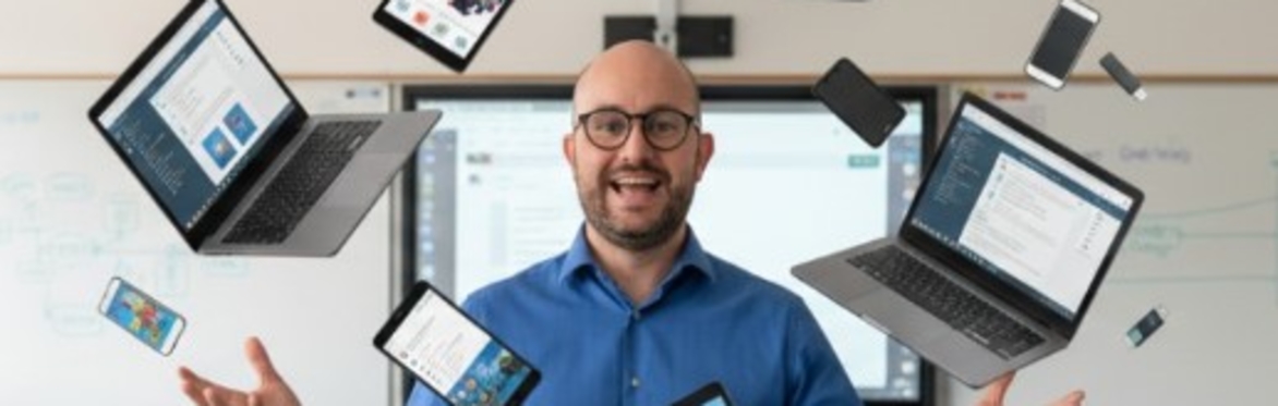 Man with various tablets and laptops circling around him