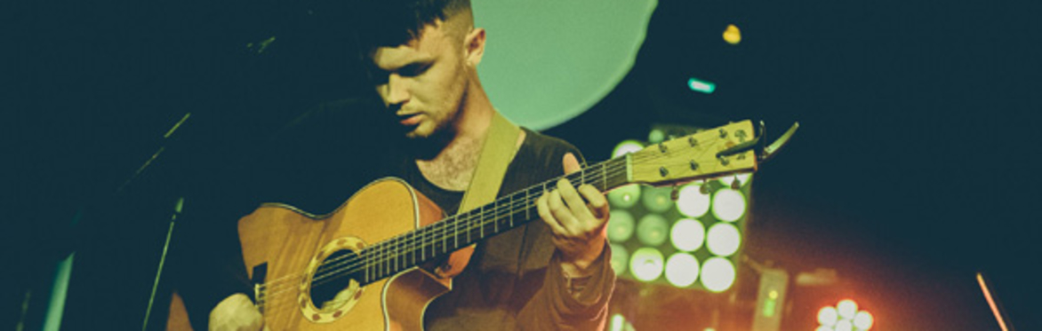 Sam looking down on his guitar onstage