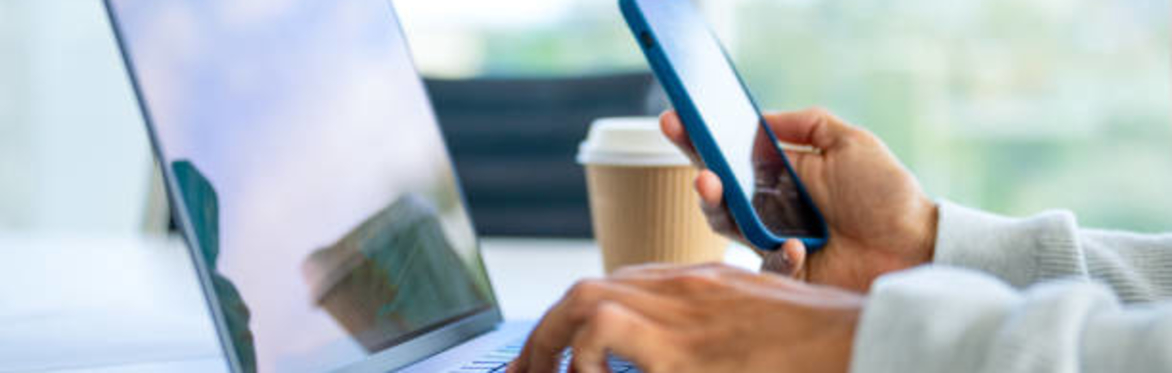 Close up of a businessman working on a laptop and holding and working on a mobile in the office