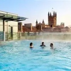 swimmers in the rooftop pool at Bath's Thermae spa with a view of the Abbey beyond
